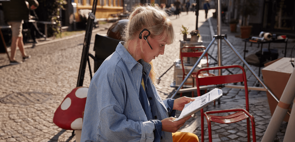 Professional using Bluetooth headphones while reading documents at an outdoor caféRetryClaude can make mistakes. Please double-check responses